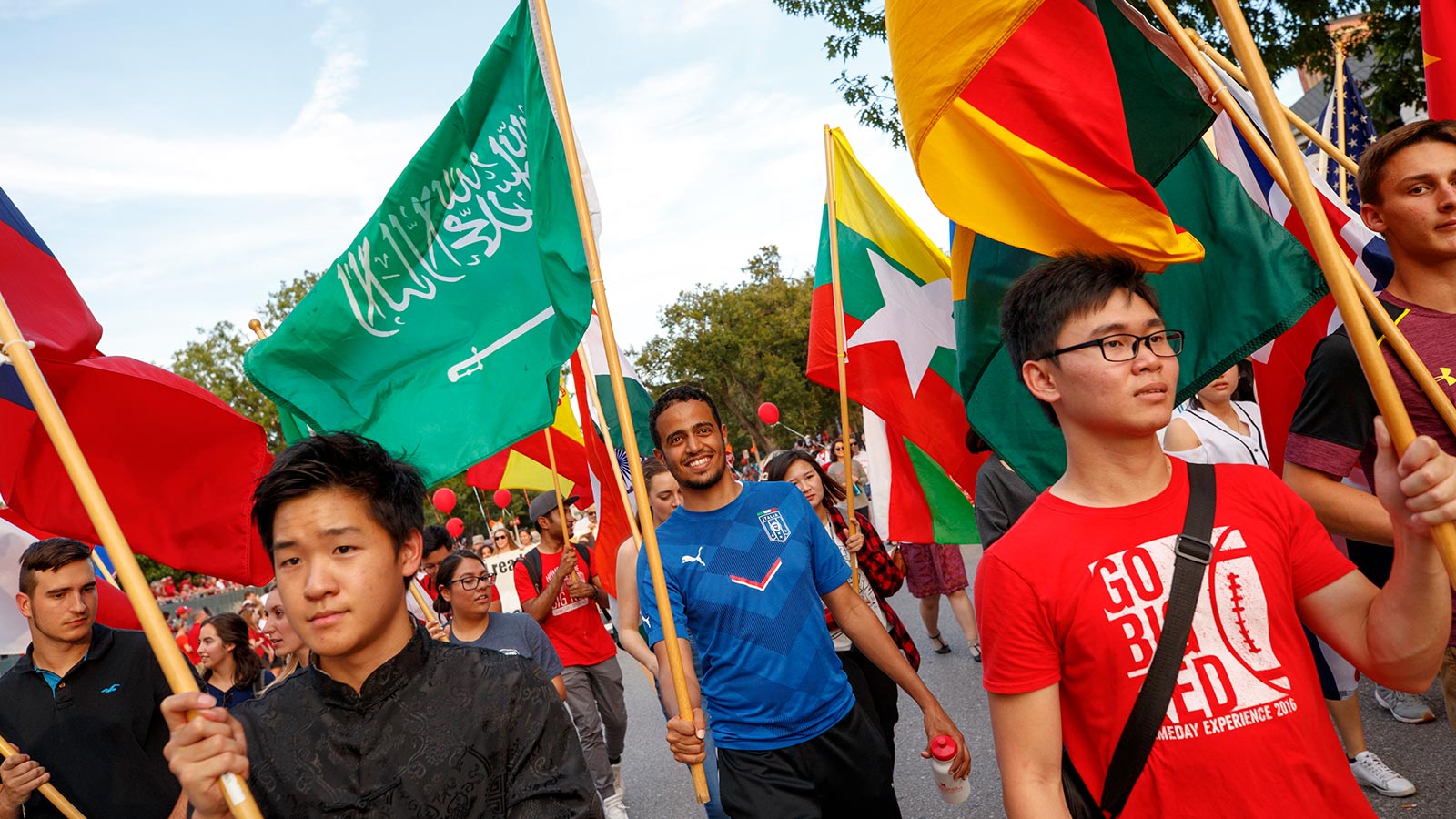 international students in homecoming parade holding country flags