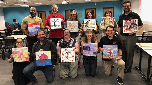 group holding up paintings they created