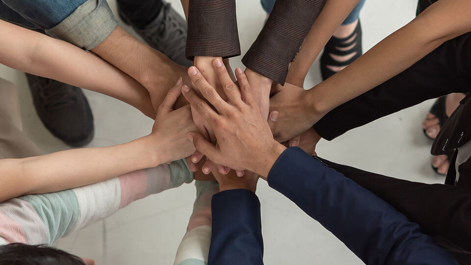 everyone standing in circle with hands on top of hands in the middle