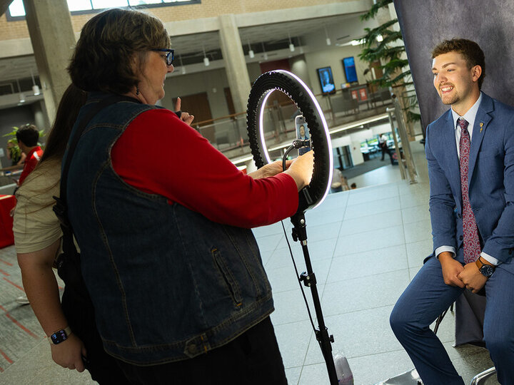 Max Muller, a junior agronomy major, poses in front of a backdrop for a portrait during the career fair held in the Nebraska East Union
