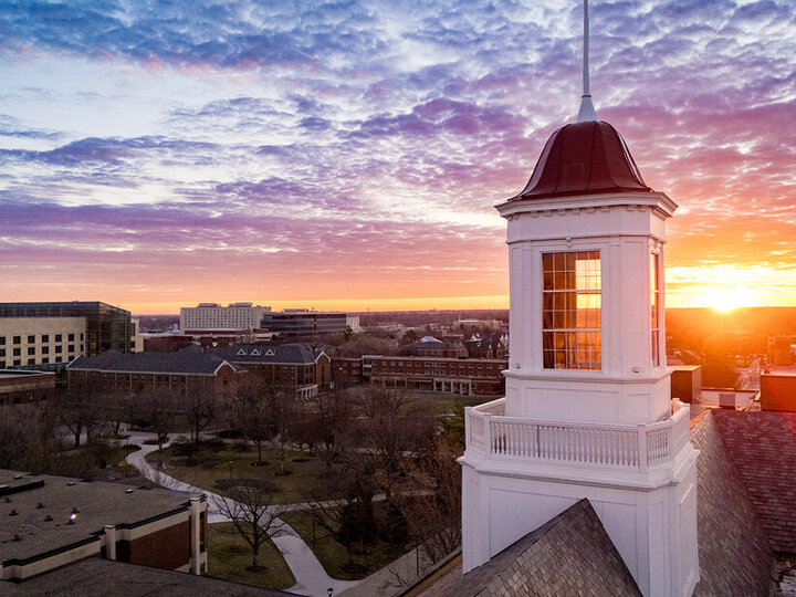 Aerial image of a sunrise over UNL's City Campus with the Love Library cupola in the foreground.