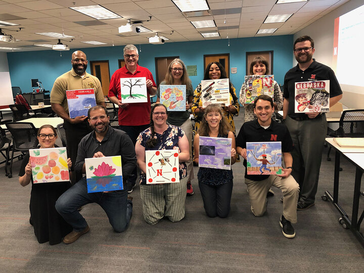 group holding up paintings they created
