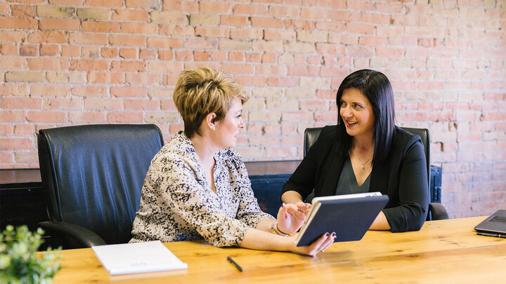 Two women in chairs in front of a table